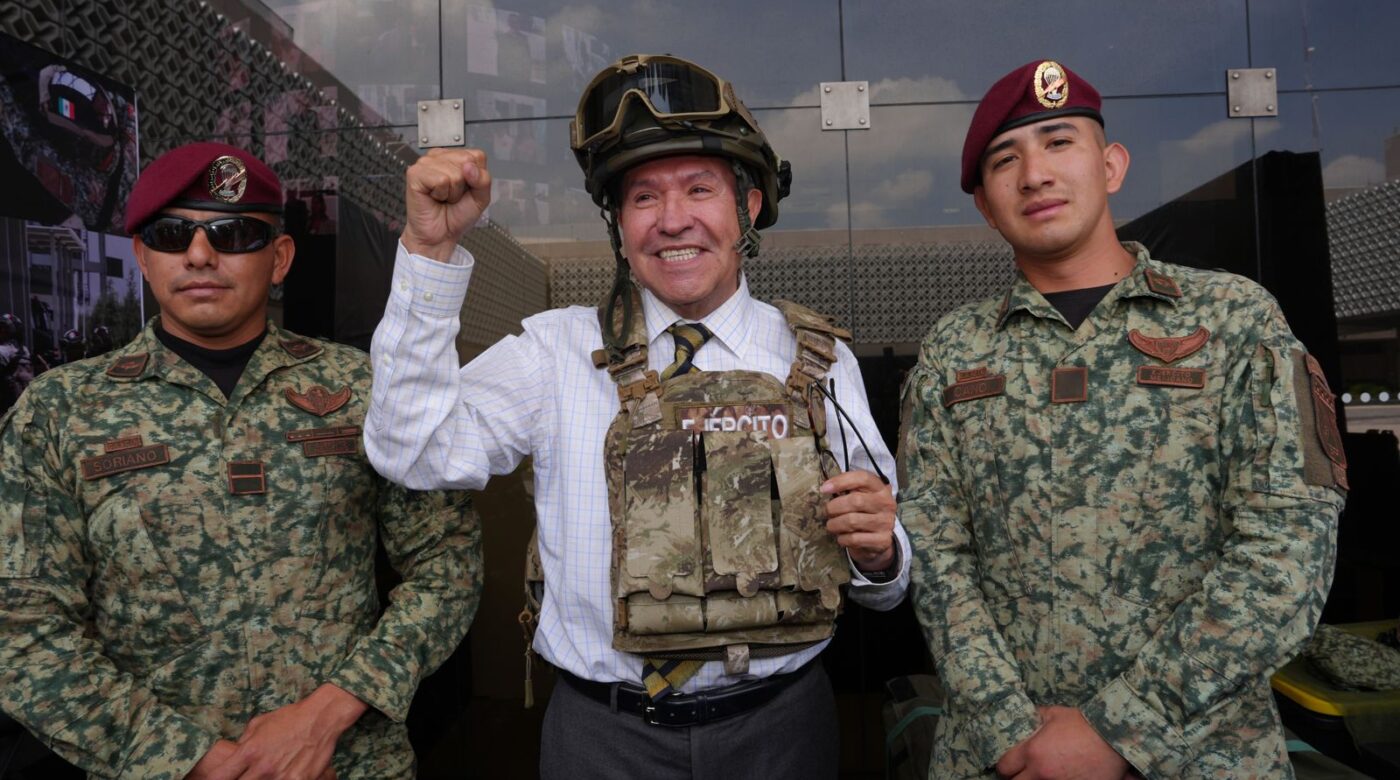 Ricardo Monreal porta chaleco y casco tácticos junto a dos militares durante una exhibición.