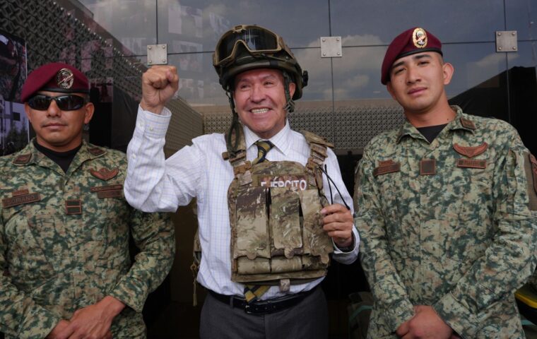Ricardo Monreal porta chaleco y casco tácticos junto a dos militares durante una exhibición.
